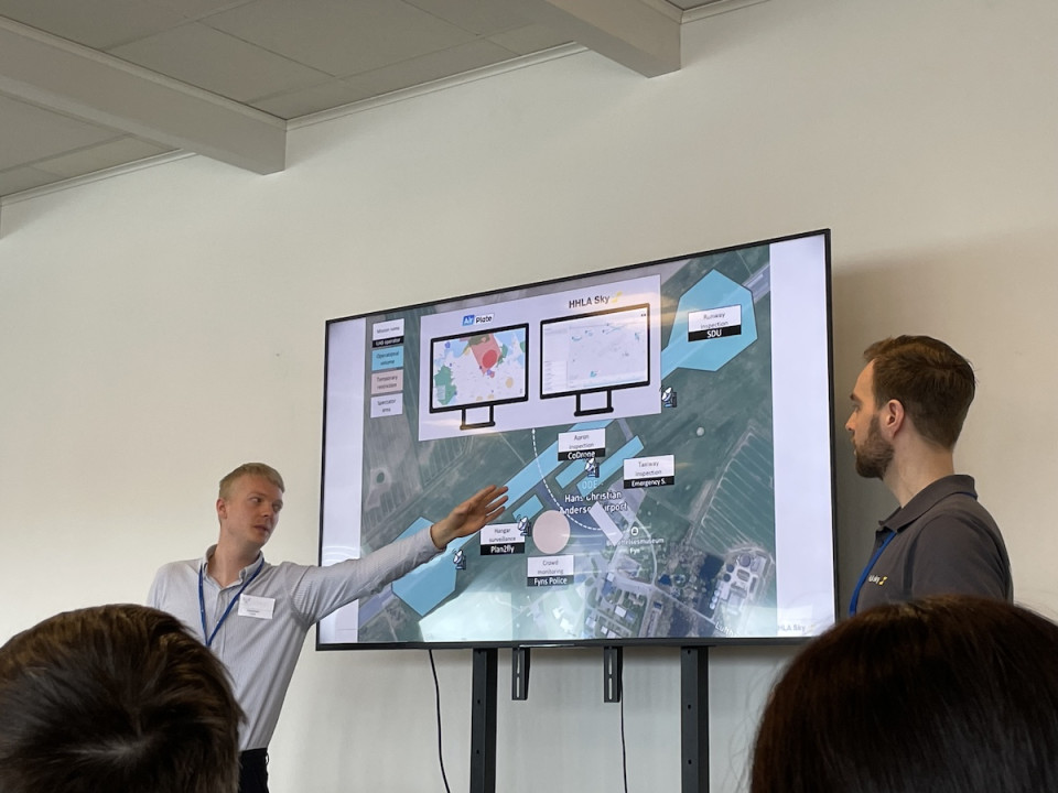 Two men presenting in front of a large screen